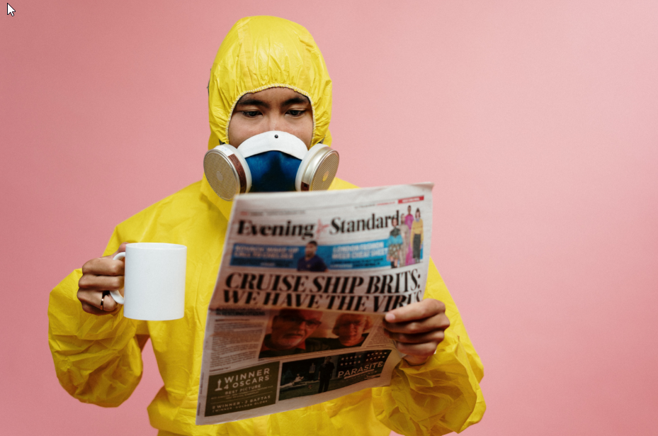 man in suit holding newspaper and mug